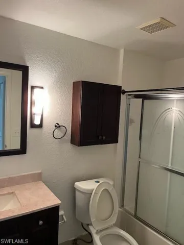 Full bathroom featuring vanity, toilet, and bath / shower combo with glass door