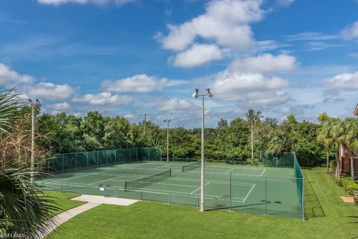 View of tennis court featuring a yard