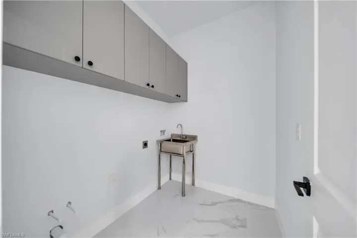 Laundry room with hookup for an electric dryer, light marble finish flooring, cabinet space, and hookup for a washing machine