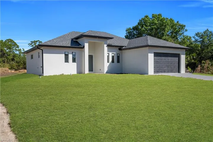 Prairie-style house featuring a front lawn, an attached garage, stucco siding, and driveway