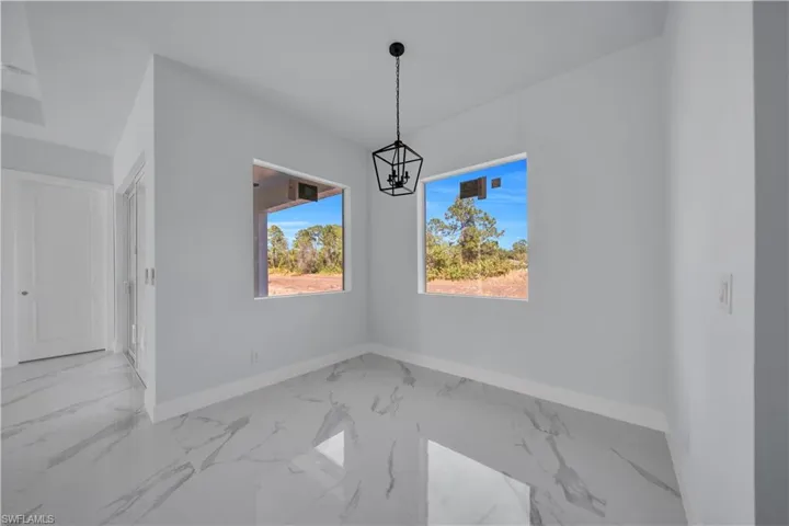 Unfurnished dining area featuring light marble finish floors and suspended lighting