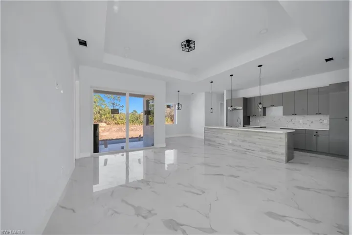 Unfurnished living room featuring baseboards and a chandelier