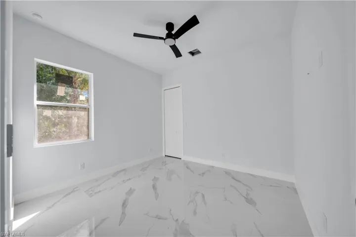Spare room featuring light marble finish flooring and ceiling fan