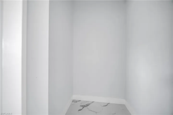 Spare room featuring baseboards and marble look tile flooring