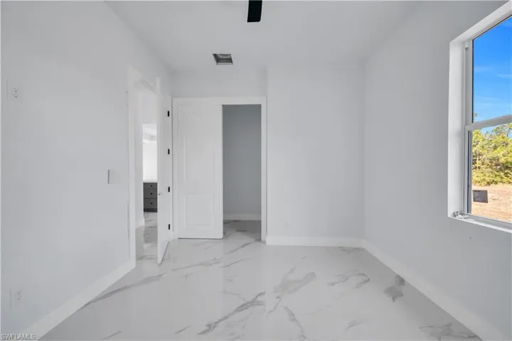Spare room featuring baseboards and light marble finish floors