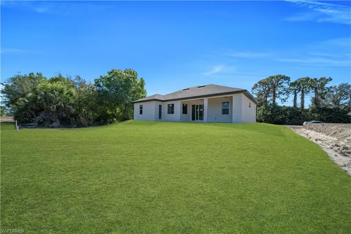 Rear view of house featuring a yard, stucco siding, and a patio area