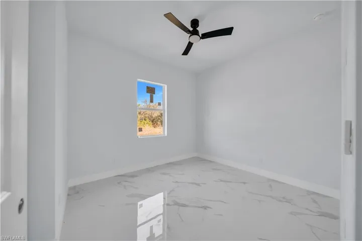 Unfurnished room featuring a ceiling fan and light marble finish floors