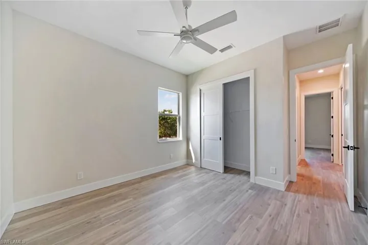 Unfurnished bedroom with light wood-style flooring, ceiling fan, and a closet