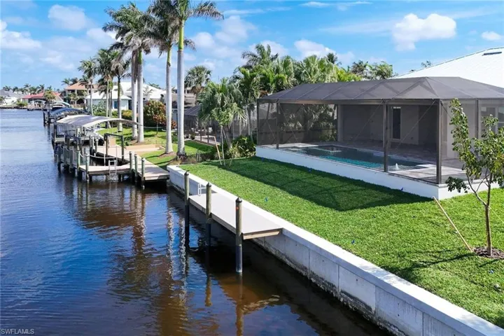Dock area with a water view, a yard, glass enclosure, boat lift, and a sunroom