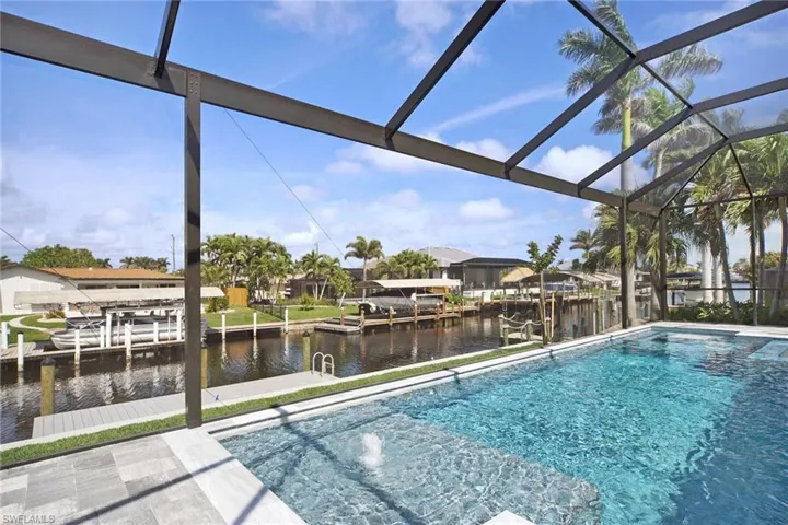 Outdoor pool with a water view, a boat dock, glass enclosure, and a sunroom