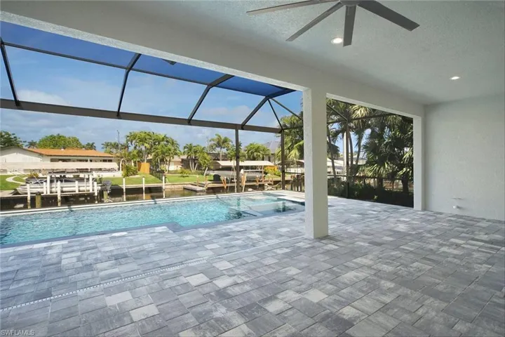 Swimming pool with a patio area, glass enclosure, boat lift, a sunroom, and a water view