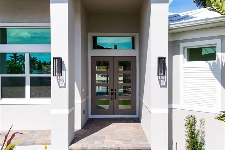 View of exterior entry with stucco siding and french doors