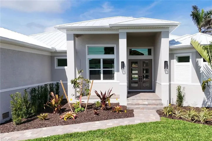 Property entrance featuring a standing seam roof, stucco siding, a metal roof, and french doors