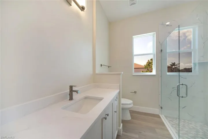 Bathroom with vanity, a marble finish shower, and light wood-type flooring