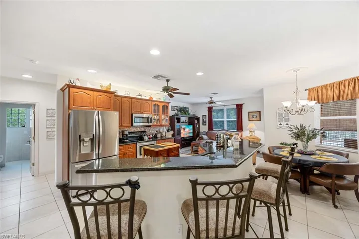 Kitchen with light tile patterned floors, a kitchen breakfast bar, appliances with stainless steel finishes, and recessed lighting