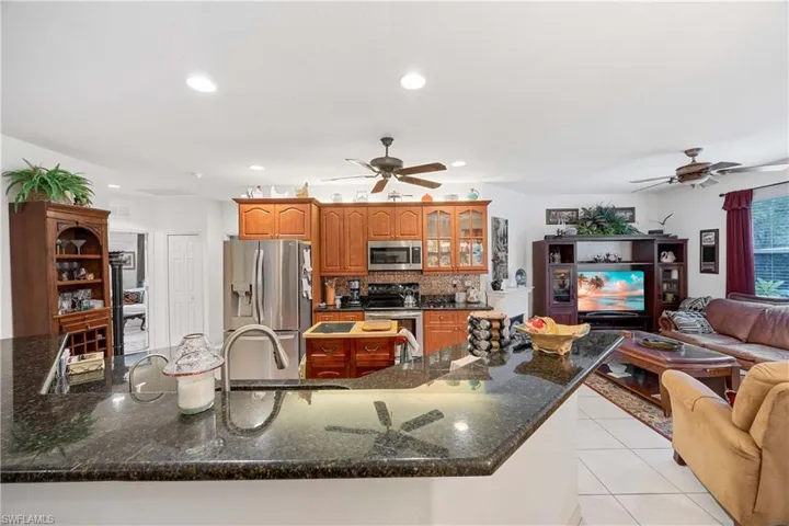Kitchen featuring open floor plan, light tile patterned floors, appliances with stainless steel finishes, recessed lighting, and glass insert cabinets