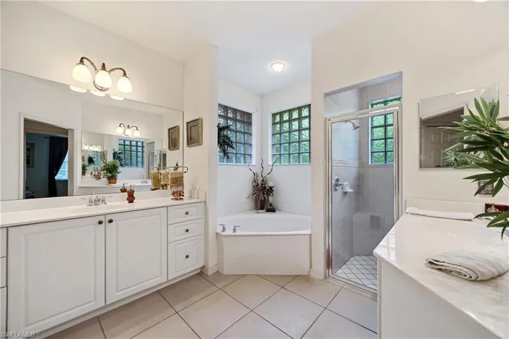 Bathroom featuring vanity, tile patterned floors, a stall shower, and a garden tub