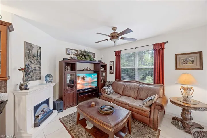 Living room featuring light tile patterned flooring, a fireplace, and a ceiling fan