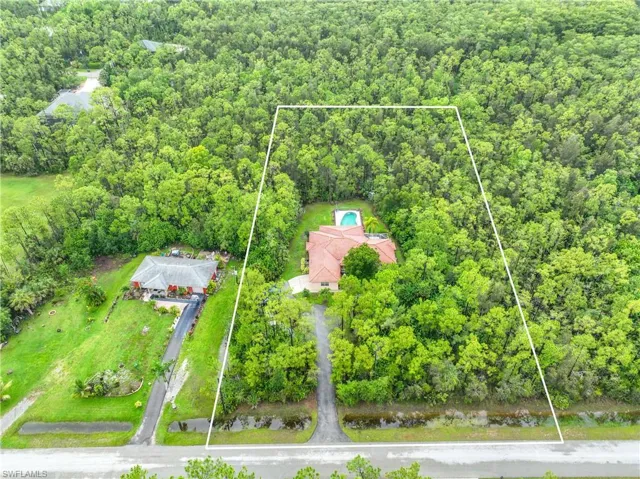 Aerial view of property's location with property parcel outlined and a heavily wooded area