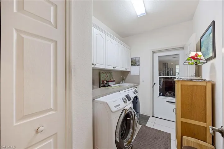 Laundry room featuring cabinet space, light tile patterned flooring, and separate washer and dryer