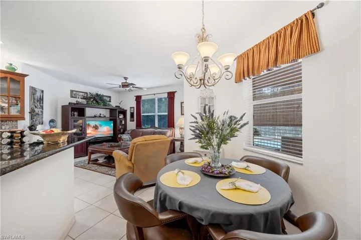 Dining space with ceiling fan, light tile patterned floors, and a chandelier
