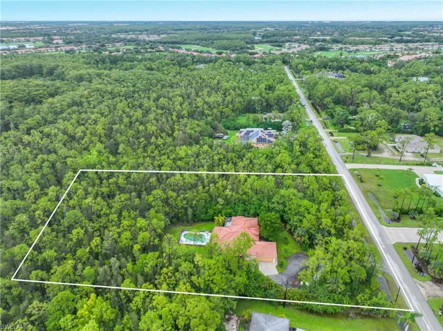 Aerial view of property and surrounding area featuring property boundaries highlighted and a heavily wooded area