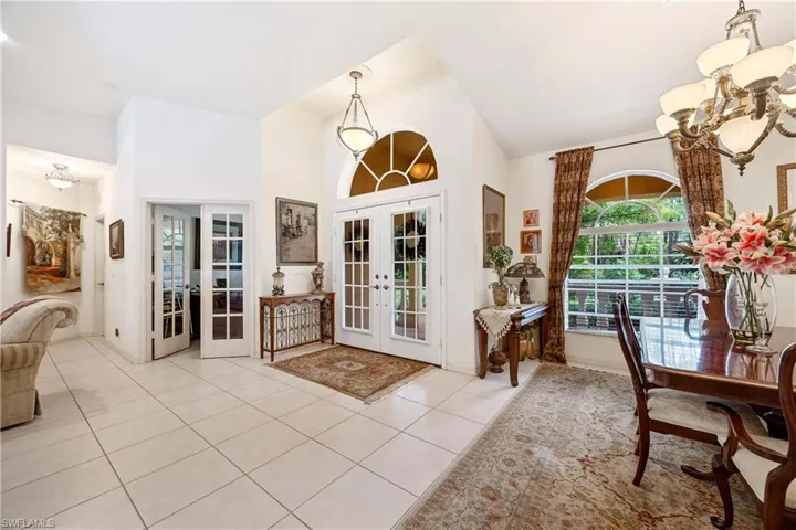 Doorway to outside featuring french doors, a chandelier, light tile patterned floors, and high vaulted ceiling