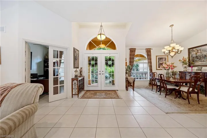 Foyer with french doors, a chandelier, light tile patterned floors, and high vaulted ceiling