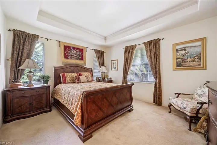 Bedroom with a raised ceiling and light carpet