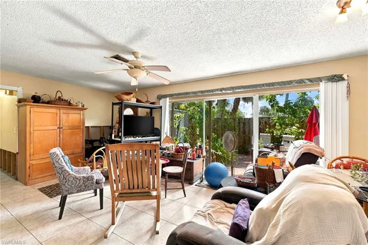 Interior space featuring large-format ceramic tile flooring, a multi-blade ceiling fan, and sliding glass doors with access to an exterior area