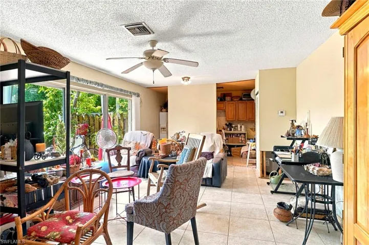Living area featuring large windows, ceramic tile flooring, and a ceiling fan with integrated lighting