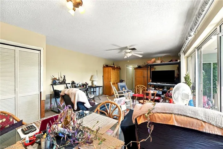 Living area featuring sliding glass doors, ceiling fan, bi-fold closet doors, and multi-light flush mount fixture