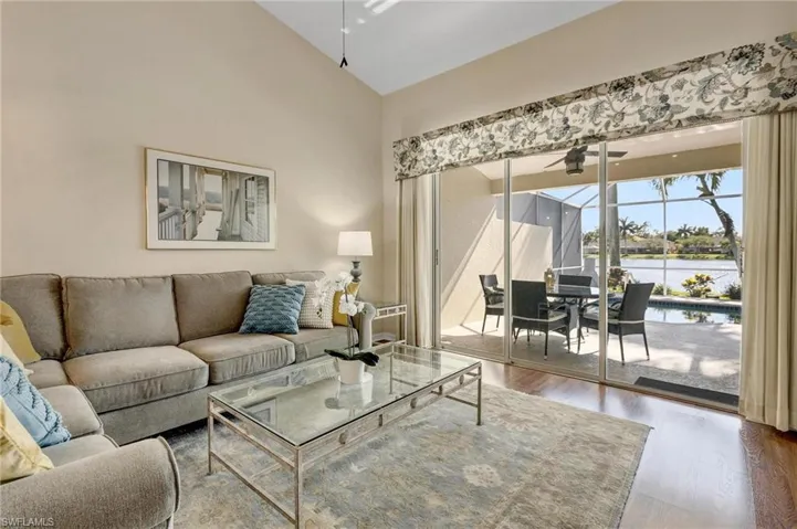 Living room featuring a water view, hardwood / wood-style floors, high vaulted ceiling, and ceiling fan