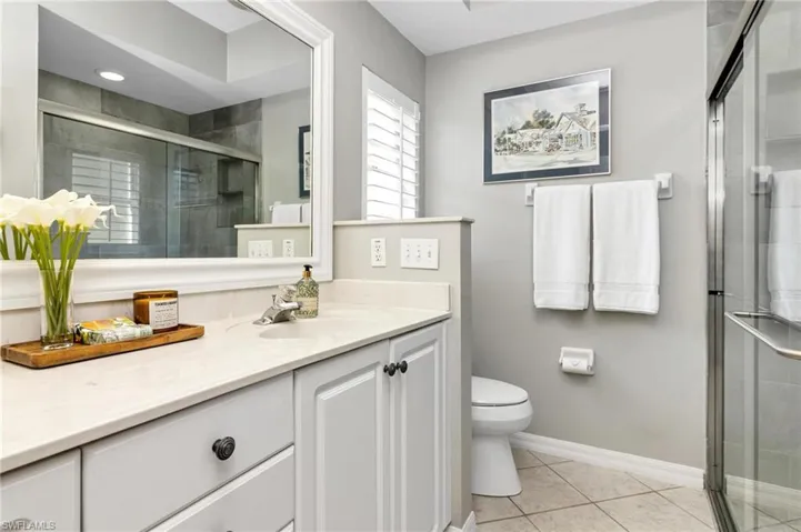 Bathroom featuring tile patterned flooring, toilet, vanity, and an enclosed shower