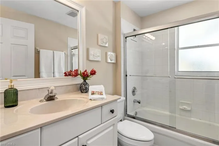 Full bathroom featuring toilet, vanity, and enclosed tub / shower combo