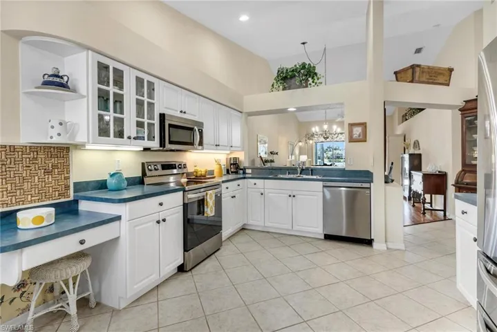 Large Kitchen featuring white cabinets, appliances with stainless steel finishes, sink, and high vaulted ceiling