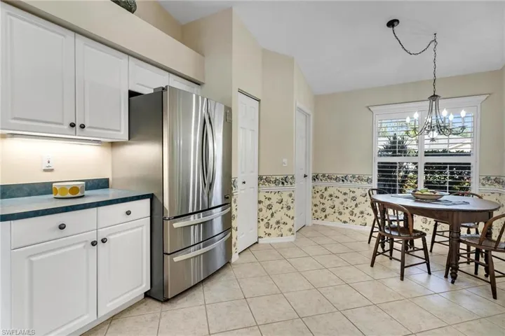 Kitchen featuring chandelier, white cabinets, stainless steel refrigerator, and light tile patterned floors