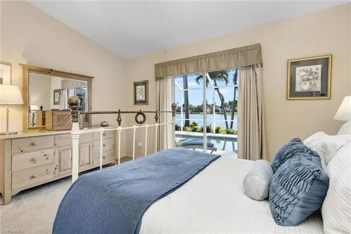 Bedroom with a water view, high ceiling, light colored carpet, and access to exterior