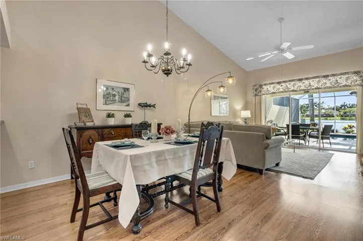 Dining room featuring high vaulted ceiling, ceiling fan with notable chandelier, and light LVP flooring