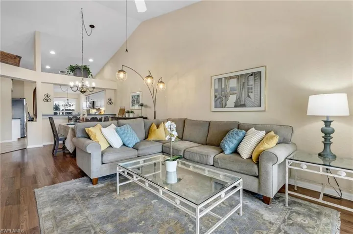 Living room featuring high vaulted ceiling, dark wood-type flooring, and a chandelier