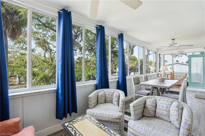 Sunroom featuring ceiling fan, outdoor dining area, and wood finished floors - Virtually Edited Image