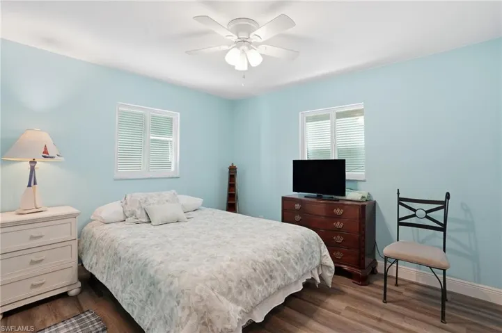 Bedroom with dark wood-style flooring and a ceiling fan - Virtually Edited Image