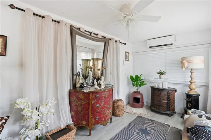Sitting room with ceiling fan, a wall unit AC, and wood finish floors - Virtually Edited Image