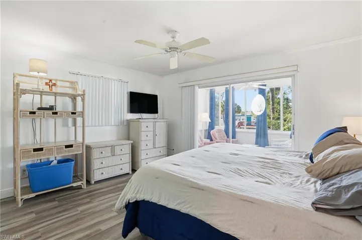 Bedroom featuring wood finished floors, access to outside, and ceiling fan - Virtually Edited Image