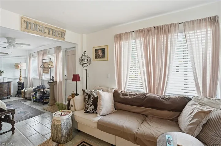 Living area with plenty of natural light, wood finished floors, and a ceiling fan - Virtually Edited Image