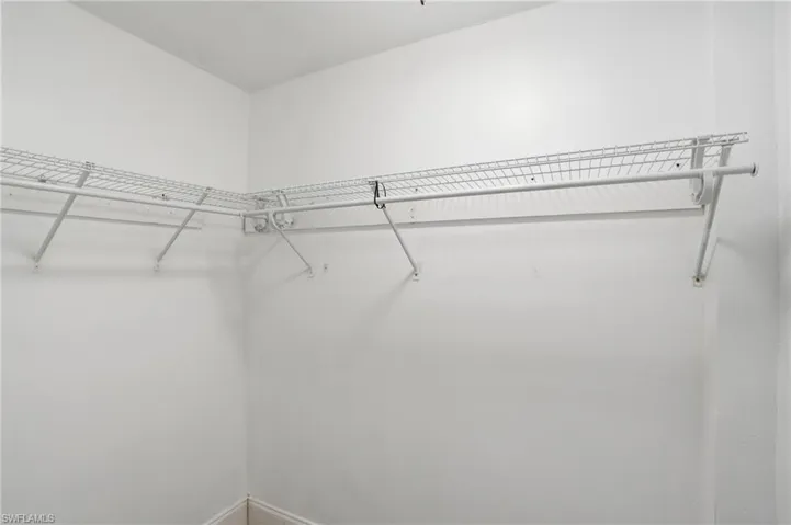 Corner closet storage featuring white wire shelving and hanging rods, providing organized space - Virtually Edited Image