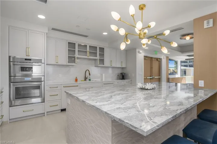 Community kitchen with a breakfast bar, decorative light fixtures, backsplash, light stone counters, and recessed lighting