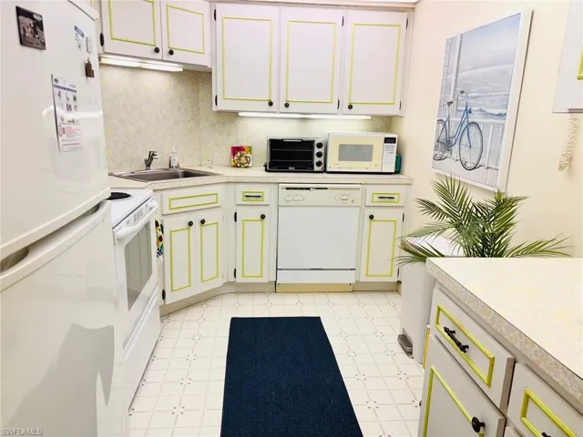 Kitchen with white appliances, light flooring, and light countertops