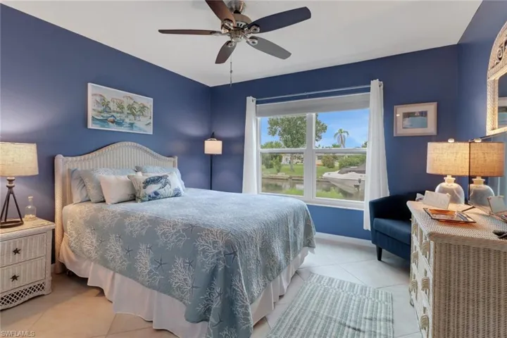 Bedroom featuring light tile patterned floors, ceiling fan, and a water view