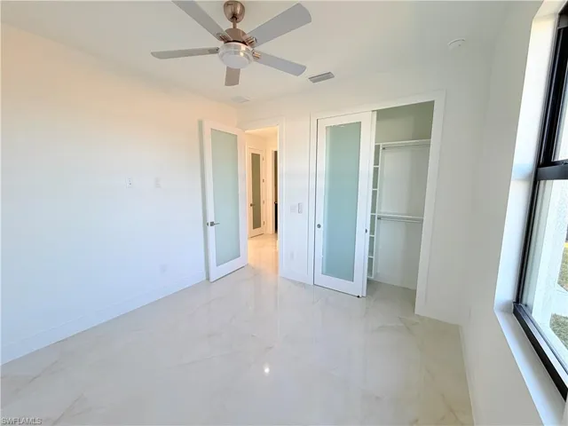 Unfurnished bedroom featuring light marble finish floors, ceiling fan, and a closet